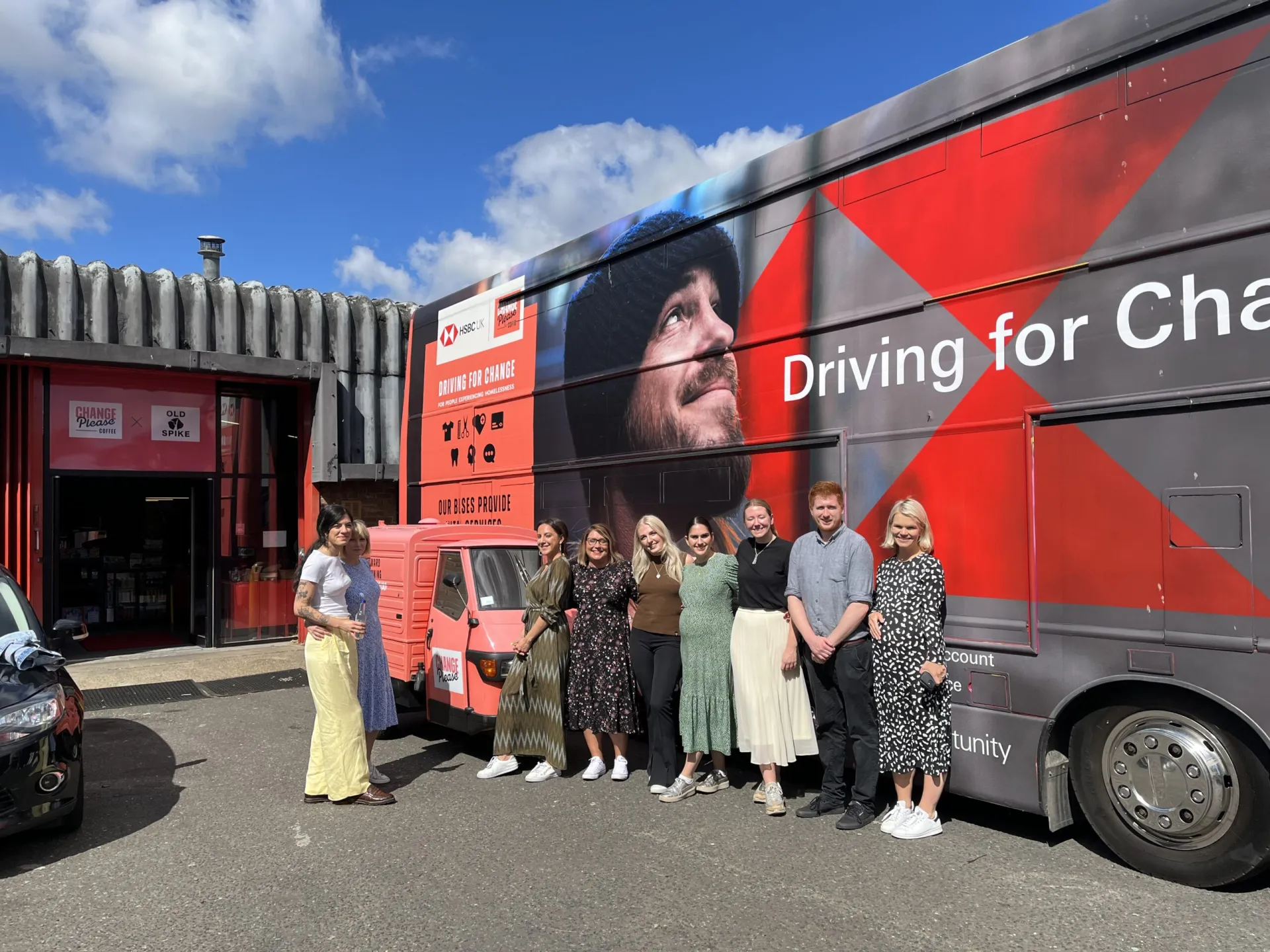 Team standing in front of the "Change Please" Bus